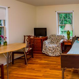 A cozy living room with a small television, wooden flooring, and various furniture pieces.