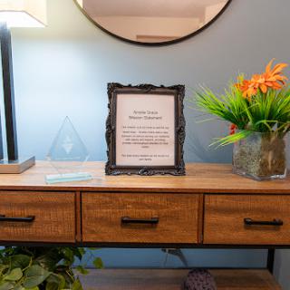A stylish living room setup featuring a decorative frame on a wooden table, accompanied by plants and a lamp.
