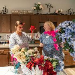 Two women engaging in floral arrangement activities in a kitchen setting.