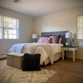 A cozy and modern bedroom with stylish decor, featuring a neatly made bed adorned with pillows and a blanket, complemented by nightstands and lamps on either side.