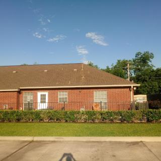 A well-maintained brick residence surrounded by greenery on a sunny day.