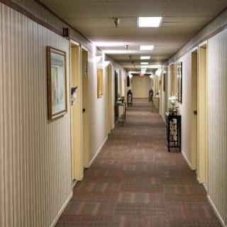 A long hotel hallway with carpeted floors and doors on each side.