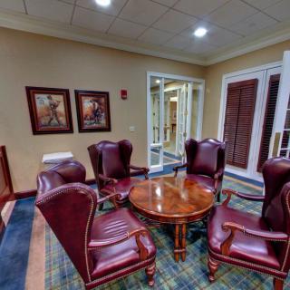A cozy lobby seating area with armchairs and a round wooden table.