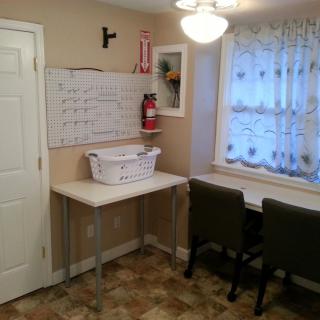 A cozy laundry room with a table, chairs, and a whiteboard.