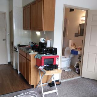 A compact and cluttered kitchenette in a small apartment space.