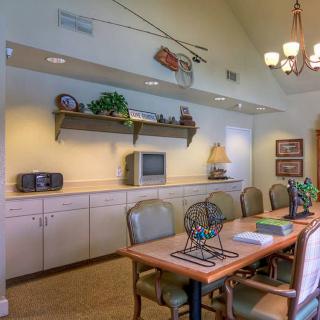 A well-lit conference room featuring a long table with chairs, decorated shelves, and a small television.