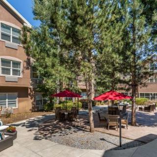 A peaceful courtyard with patio furniture and red umbrellas surrounded by apartment buildings.