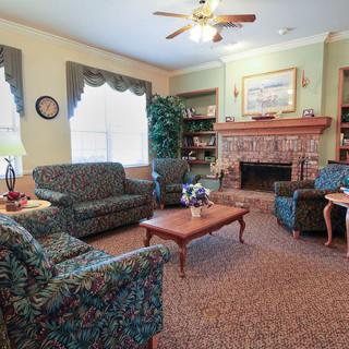 A cozy living room with patterned furniture, a fireplace, and large windows.