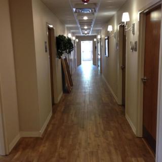 A well-lit hallway with wooden flooring and multiple doors on each side.
