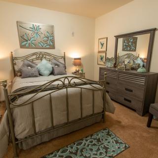 A cozy bedroom with decorative elements, featuring a bed, dresser, and warm lighting.