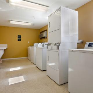 A well-equipped laundry room featuring multiple washing machines and dryers.