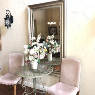A charming corner with a floral centerpiece and elegant seating, reflected beautifully in the mirror.