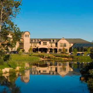 A serene hotel exterior reflecting beautifully on the calm waters of a nearby pond.