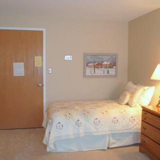 A simple, cozy bedroom with a neatly made bed and a bedside lamp.