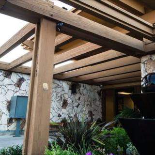 A pergola with wooden beams and lush greenery in a garden setting.