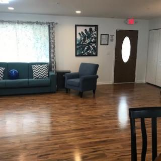 A cozy living room with a sofa, armchair, and wooden flooring.