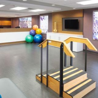 A well-equipped physical therapy room with exercise balls and a rehabilitation staircase.
