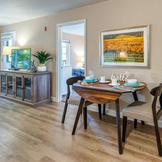 A stylish dining area with a wooden table and modern chairs, featuring vibrant artwork on the wall.