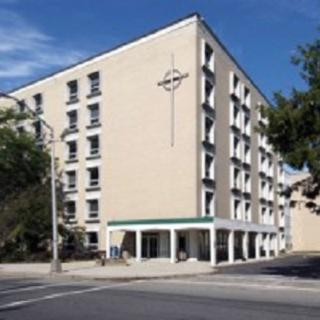A modern hotel building located at a street corner under a clear blue sky.