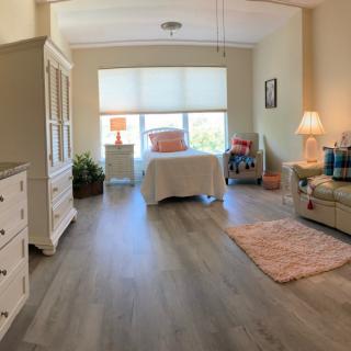 A cozy and well-lit bedroom with stylish decor and wooden flooring.