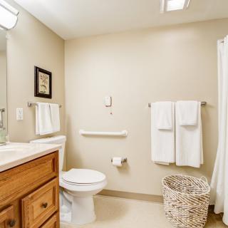 A clean and minimalist bathroom with beige walls, a vanity sink, and neatly hung towels.