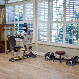 A well-lit home gym with various exercise equipment and weights.
