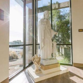 A statue illuminated by sunlight stands near a large window in an interior space.