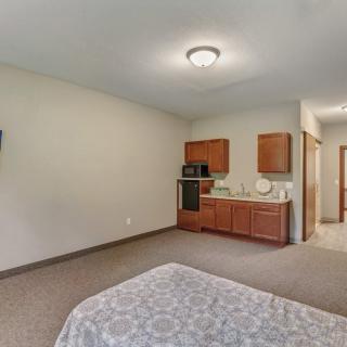 A minimalist bedroom with a kitchenette and neutral color scheme.