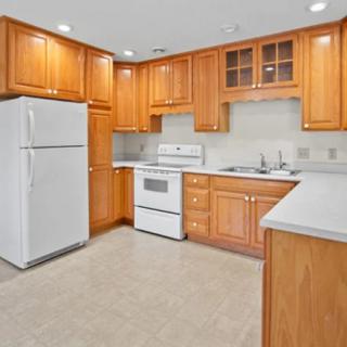 A spacious kitchen with wooden cabinets and white appliances.