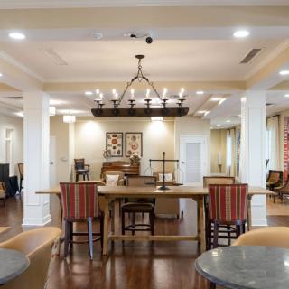 A spacious dining room with elegant decor, featuring a large wooden table, chairs with striped cushions, and a central chandelier.