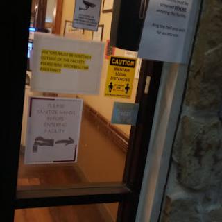 A view of the entrance door with various informational and warning signs displayed.
