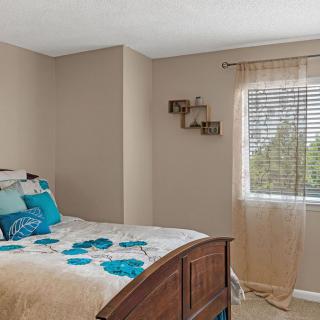 Cozy bedroom with a neatly made bed and natural light streaming through the window.