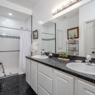 A modern bathroom with a double vanity and spacious shower area.