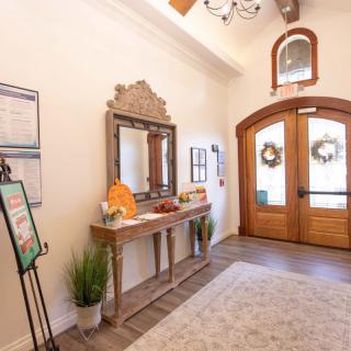 A welcoming entryway with a wooden door, decorative mirror, and potted plant.