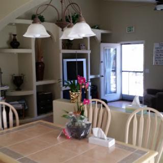 A cozy dining area with a table, flowers, and warm lighting.