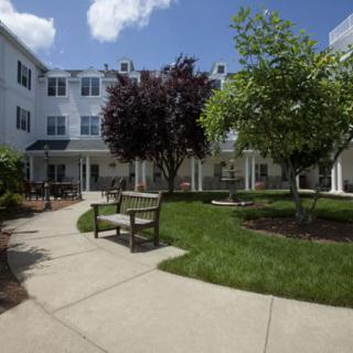 A peaceful courtyard with benches and trees outside a multi-story building.