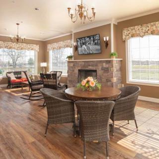A cozy living room with a fireplace, round dining table, and large windows.