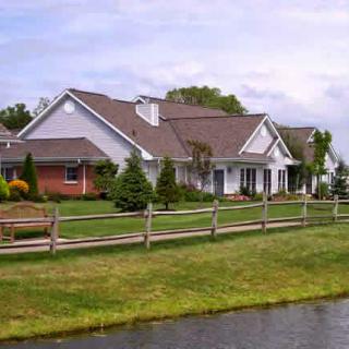 A beautiful residential house surrounded by a well-maintained lawn and fence.