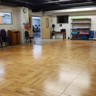 An empty room with a wooden floor and chairs, likely used for meetings or community activities.