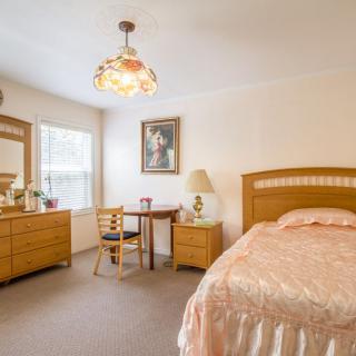 A cozy bedroom with a bed, dresser, and small table with chairs.