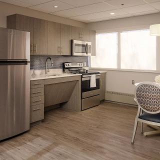 A modern kitchen with stainless steel appliances and a small dining area.