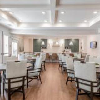 A modern dining area with neatly arranged tables and chairs, featuring elegant lighting.
