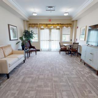 A spacious living room with comfortable seating and a television, featuring large windows and elegant decor.