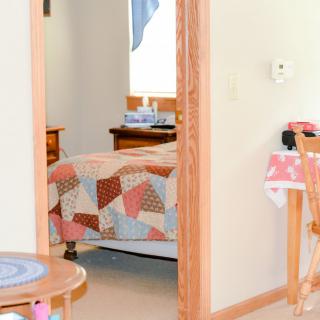 A cozy bedroom with a colorful quilt on the bed and warm wooden furniture.