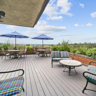 A spacious outdoor patio with comfortable seating and umbrellas under a partly cloudy sky.