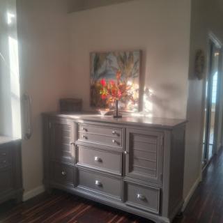 A stylish dresser in a well-lit hallway, adorned with decorative elements and a vibrant piece of wall art.