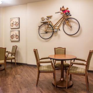 A cozy cafe interior featuring a bicycle mounted on the wall as decoration, accompanied by tables and chairs on a wooden floor.