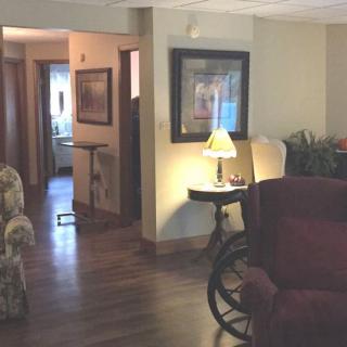 A cozy living room with warm lighting, featuring a lamp on a side table and wheelchair access.