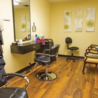 Interior view of a hair salon with styling chairs, a mirror, and a waiting area.