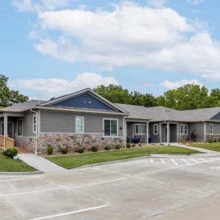 A suburban residential building with a driveway and landscaped surroundings.